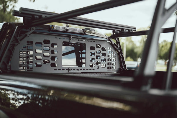 HeadBANGER — Lifestyle shot: viewed from inside the cab, guard mounted behind the rear window under the ACS FORGED crossbars on a parked truck.