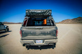 Leitner ACS Forged NDNS — Feature shot: rear view of a Ford Raptor with a rooftop tent, GearPod box, and MaxTrax boards permanently mounted on the fixed load bars