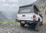 Backwoods Adventure Mods Hi-Lite Rear Bumper (2016–2023 Tacoma) — Lifestyle shot: Tacoma with the rear bumper on a mountain road
