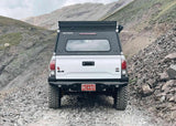 Backwoods Adventure Mods Hi-Lite Rear Bumper (2016–2023 Tacoma) — Lifestyle shot: white Tacoma with the rear bumper on a mountain trail