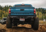 Backwoods Adventure Mods Hi-Lite Rear Bumper (2016–2023 Tacoma) — Lifestyle shot: blue Tacoma with the rear bumper pushing through mud