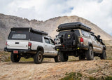 Backwoods Adventure Mods Hi-Lite Rear Bumper (2016–2023 Tacoma) — Lifestyle shot: two Tacomas fitted with the Hi-Lite rear bumper