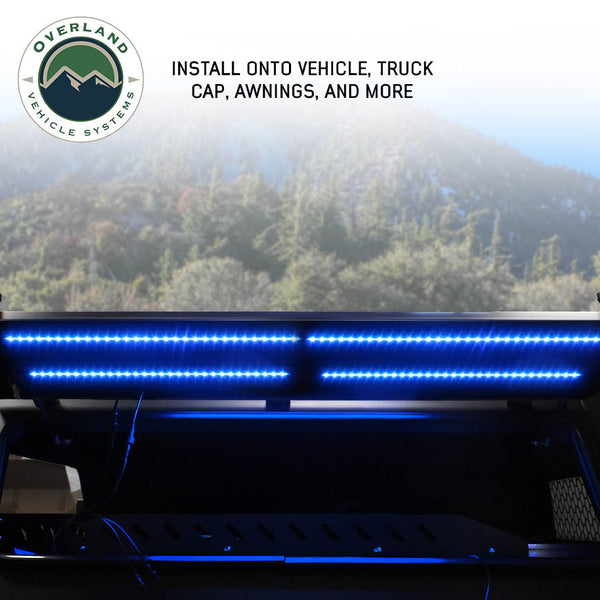 OVS 4 Piece LED Light Kit — Lifestyle shot: LED light bars glowing blue under a truck at a forest overlook, lighting camp after dark