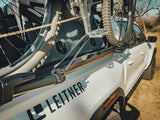 KUAT Piston SR Bike Tray — Lifestyle shot: close-up of a bike's rear wheel and chain held in the tray on a truck bed rail, tire arm gripping the wheel without touching the frame