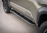 Backwoods Adventure Mods Rock Sliders (2024–2027 Tacoma) — Feature shot: front of the slider by the Tacoma badge