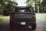 HeadBANGER — Lifestyle shot: rear view of a black Ford Raptor with the guard mounted behind the cab as part of the full ACS FORGED rack.
