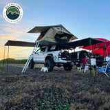 OVS HD Nomadic 90 Awning — Lifestyle shot: pickup with a rooftop tent and awning set up at a lakeside camp. Easy add-on shade for truck campers