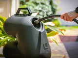 HydroPOD CARRY Portable Shower Kit — Lifestyle shot: a woman pumps the unit stowed in her open hatchback trunk to rinse off after a day at the beach.