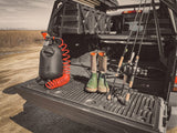 HydroPOD CARRY Portable Shower Kit — Lifestyle shot: a woman rinses sand off her foot in her driveway using the hose, bodyboards and an open hatchback nearby.