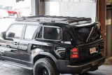 Backwoods Adventure Mods DRIFTR Roof Rack (2024–2027 GX550) — Lifestyle shot: using the grab handle to reach roof cargo