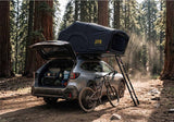 Roofnest Meadowlark 2 XL — Lifestyle shot: open tent on a Subaru with bikes at a redwood forest campsite. A roomy weekend setup for small families.