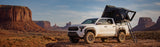 Roofnest Condor Overland 2 Air — Lifestyle shot: open aluminum-shell tent on a white pickup below red-rock buttes, built for long dirt-road trips
