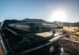 Roofnest Falcon 3 EVO Air — Lifestyle shot: closed tent on a pickup bed rack in the desert at sunset. A low-profile setup for long overland drives.