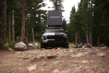 FSR Aspen Pro — Lifestyle shot: Aspen Pro open on a pickup at a truck camping setup, a low-profile aluminum clamshell for one or two