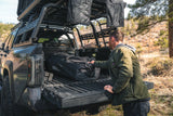 FSR Hub 4 Double — Lifestyle shot: packed storage bag being unloaded from a truck bed at a wooded campsite.