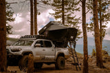 FSR Kali — Lifestyle shot: installed on a Tacoma bed rack in a wooded campsite with mountains in the background