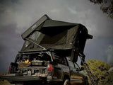 FSR Kali — Lifestyle shot: Kali deployed on an overland Toyota Tacoma bed rack under a cloudy sky, a compact fold-out for two to three on mid-size trucks