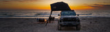 Roofnest Meadowlark 2 XL — Lifestyle shot: open tent on a pickup on a beach at sunset with camp chairs out, room for three