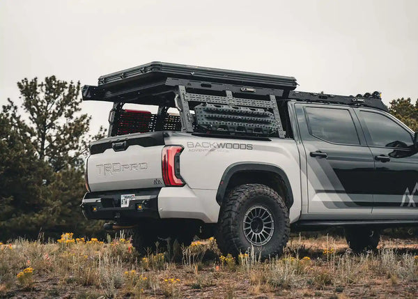 Backwoods Adventure Mods Overland Bed Rack Full Height (2007–2027 Tundra) — Lifestyle shot: Tundra off road with a rooftop tent, awning, fuel cans and traction boards on the rack